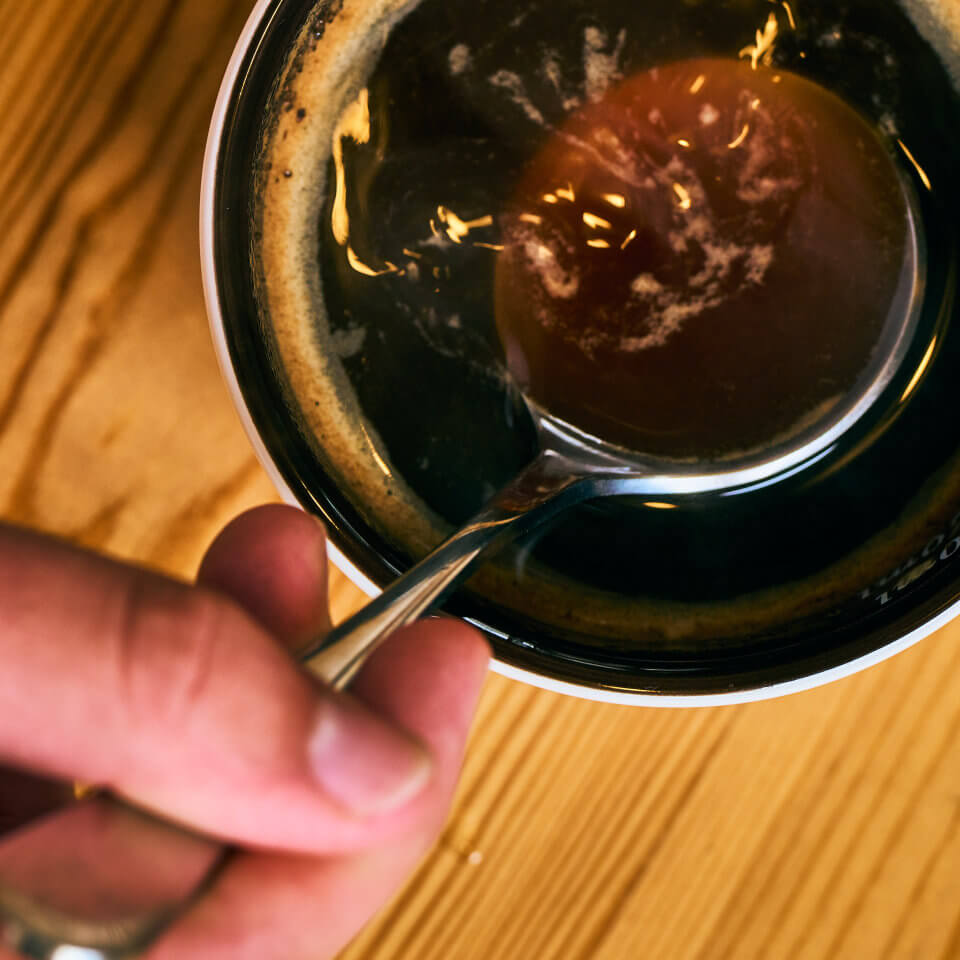 A spoon is submerged into the freshly prepared tasting sample for quality control.