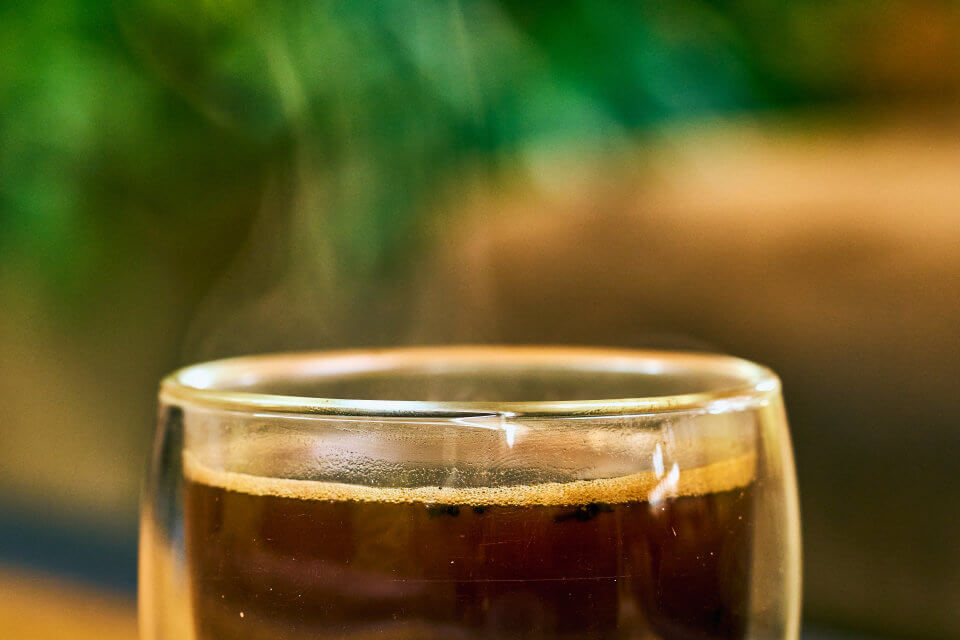 A freshly poured coffee against green foliage.